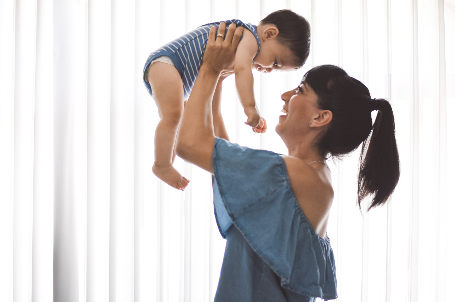 a young mother holds her baby up