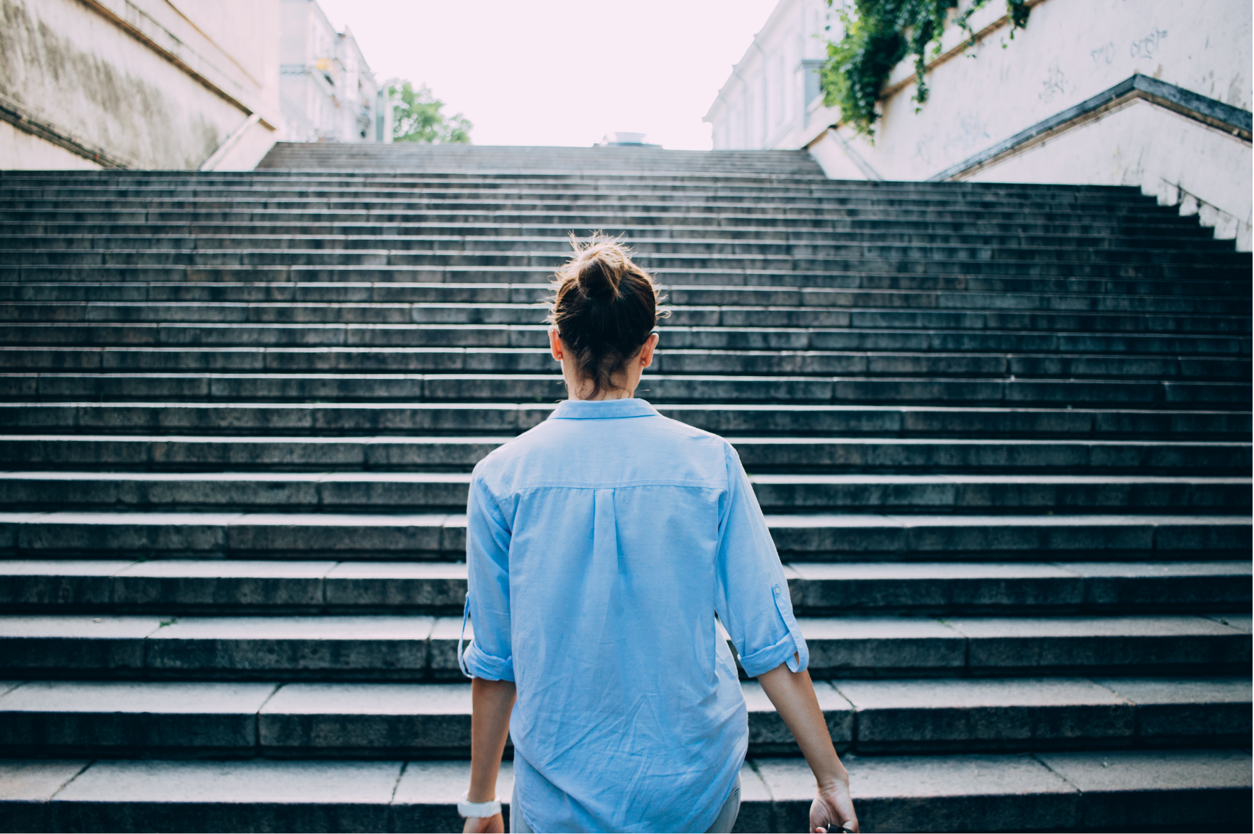 A woman stands before a large, imposing concrete stairway